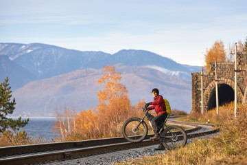 Obraz premium Tourist rides a bike with wide wheels along the shore of Lake Baikal.
