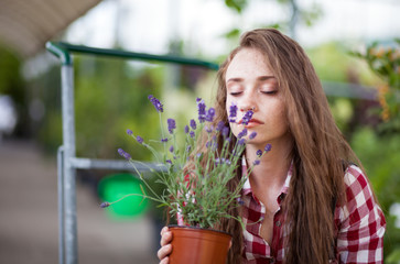 Young woman in garden center smelling flowers of potted lavender