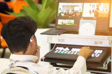 Technicians are controlling video production. Live broadcast controllers tuned to be usable. Behind the televised broadcast in the control room with  video switcher.