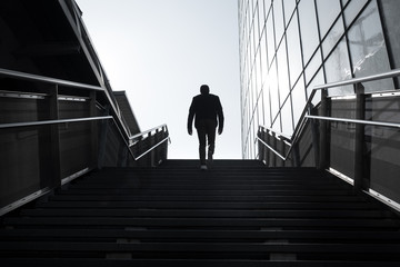 avenir silhouette homme marche escalier avancer perspective demain travailler projet construire seul solitude aide aider marcher monter gravir effort immeuble façade moderne building dos