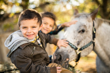 in a beautiful Autumn season of a young brother and sister with horse