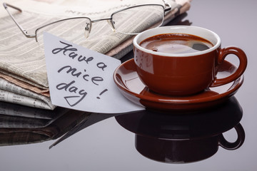 Cup of coffee with newspaper and note.
