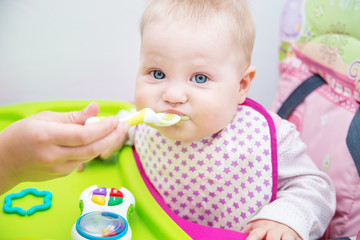 The baby learns to eat from a spoon. The first lure of the baby.
