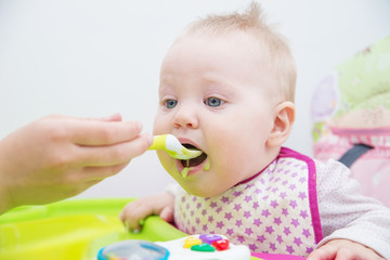 The baby learns to eat from a spoon. The first lure of the baby.