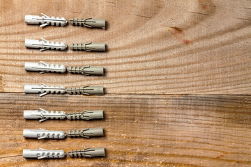 Plastic dowels lie in a row on a wooden background