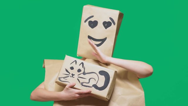concept of emotions, gestures. a man with a package on his head, with a painted emoticon, smile, loving eyes. plays with a cat drawn on the box.