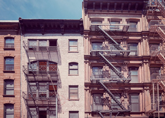 Old buildings with fire escapes, one of the New York City symbols, vintage toning applied, USA.