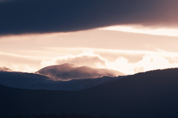 Dramatic winter storm blows over a cold barren landscape at sunset