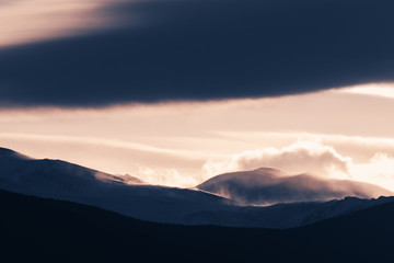 Dramatic winter storm blows over a cold barren landscape at sunset