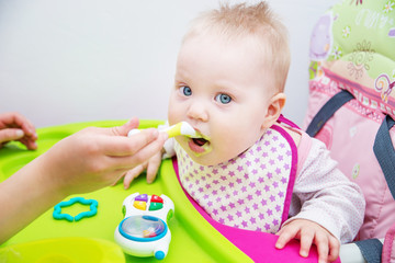 The baby learns to eat from a spoon. The first lure of the baby.