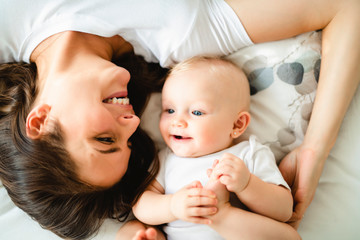 mother with baby on bed having good time