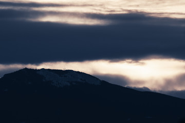 Dramatic winter storm blows over a cold barren landscape at sunset