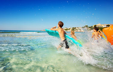 Teenage boys splashing while running into the sea