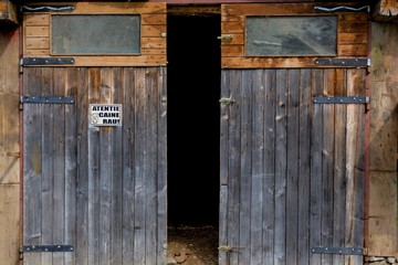Rustic old wooden barn doors on a farm with beware bad dog sign. Wooden farm gate.