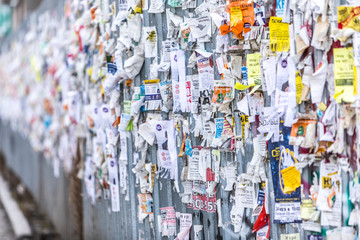 A part of a long wall with advertisements consisting of small pieces of paper