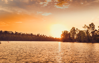 Fototapeta premium Great sun on the horizon illuminating the lake