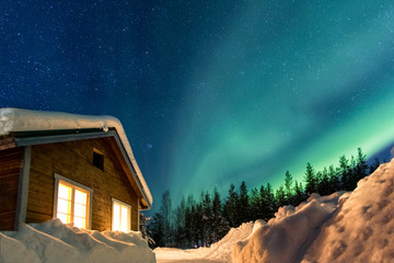 Fototapeta premium Winter landscape with wooden house under a beautiful starry sky and Northern Lights