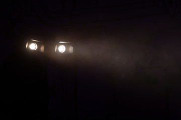 Two white stage lights in a dark environment