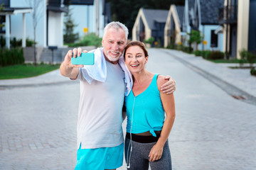 Selfie after running. Modern couple of mature businessmen making selfie after running around their residential area together