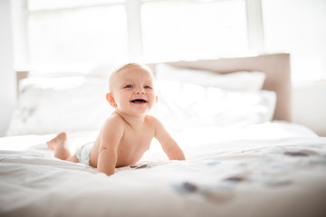 Cute baby girl lying on white sheet at home