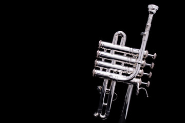A silver plated piccolo trumpet on a black background