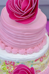 Close up of a party cake with pink flower decorations and frosting