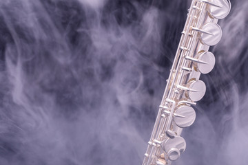 A silver plated alto flute in smoke on a black background © Janisphoto