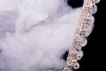 A silver plated alto flute in smoke on a black background © Janisphoto