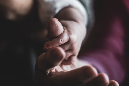 baby hand holding grandmother's finger