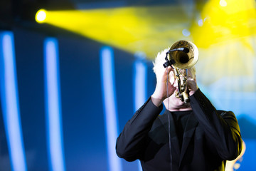 A trumpet player performing in a concert with stage lights in the background