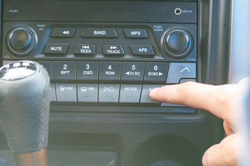 close up person's hand push the car radio stereo system, searching for song f