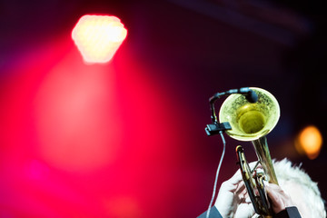 A trumpet player performing in a concert with stage lights in the background