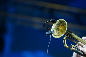 A trumpet player performing in a concert with stage lights in the background