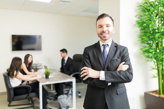 Confident Boss Smiling While Team Working In Office