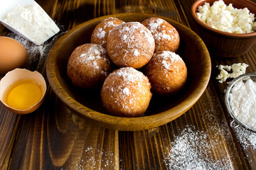 Homemade cottage cheese donuts and ingredients on the brown wooden background