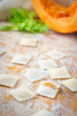 traditional raw ravioli with pumpkin on a wooden table with flour, handmade, cooking process