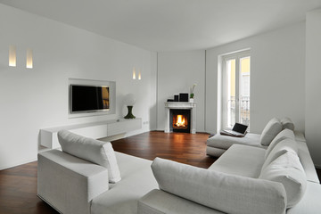 modern living room with wooden floor in the foregound a big fabric sofa on the background the ancient fireplace also on the wall in front of the sofa the led television