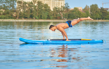 Man practicing yoga, doing balance body weight smimming on paddle board.
