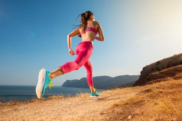 Abwaschbare Fototapete Joggen Frau läuft. Junge Läuferin joggt auf einem Bergpfad in der wunderschönen Landschaft. Gesunder sportlicher Lebensstil. Fitness und Training im Freien