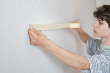 male worker using the masking tape to paint the wall  f