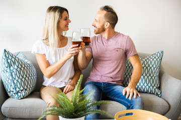 Relaxed young couple watching tv and drinking beer at home