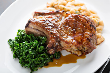 Grilled pork chop with cassoulet and braised greens