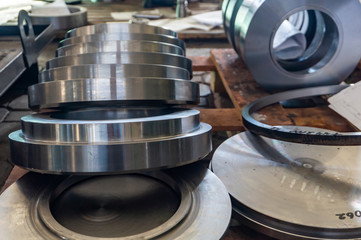 Round parts with drawings after turning are on a wooden rack in the workshop.