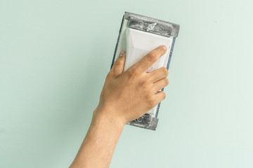 worker holds a trowel to finish plastering the wall, repairing home concept