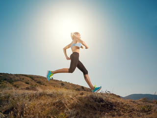 Woman running. Young girl runner jogging on a mountain trail in the beautiful landscape. Healthy sport lifestyle. Fitness and workout on outdoors.
