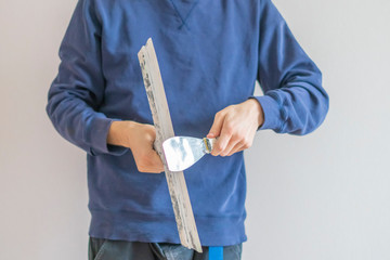 close up man holding putty knifes plastering the wall, working and repair home f