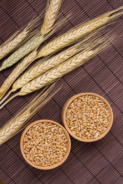 Wheat grains and spikelets of wheat on a brown background. Top view