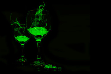 Green glowing phosphorescent rocks in wine glasses with smoke