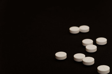 Fototapeta na wymiar A handful of pills on black background