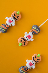 Halloween candies arranged in an alternating pattern on an colored background